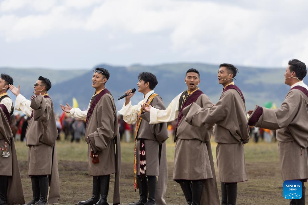 Tamdrin (tengah) bersama-sama dengan penyanyi tempatan bernyanyi di sebuah balapan lumba kuda di Kaunti Litang, Wilayah Autonomi Tibet Garz, Provinsi Sichuan, barat daya China pada 30 Julai 2024. Tamdrin merupakan pengembala dari sebuah kampung di Kaunti Litang. Beberapa tahun lalu, dia menjadi sensasi media sosial di China dan kini merupakan duta pelancongan bagi kaunti halamannya iaitu Litang. Satu acara lumba kuda membuka tirainya di Kaunti Litang pada Selasa, menarik penyertaan hampir 1,000 pengembala dari serata kaunti dalam pelbagai aktiviti. (Xinhua/Jiang Hongjing)